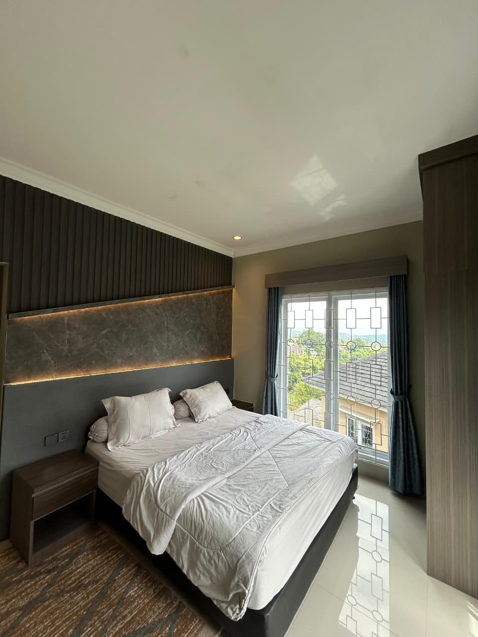 King bed with backlit headboard and curtained window