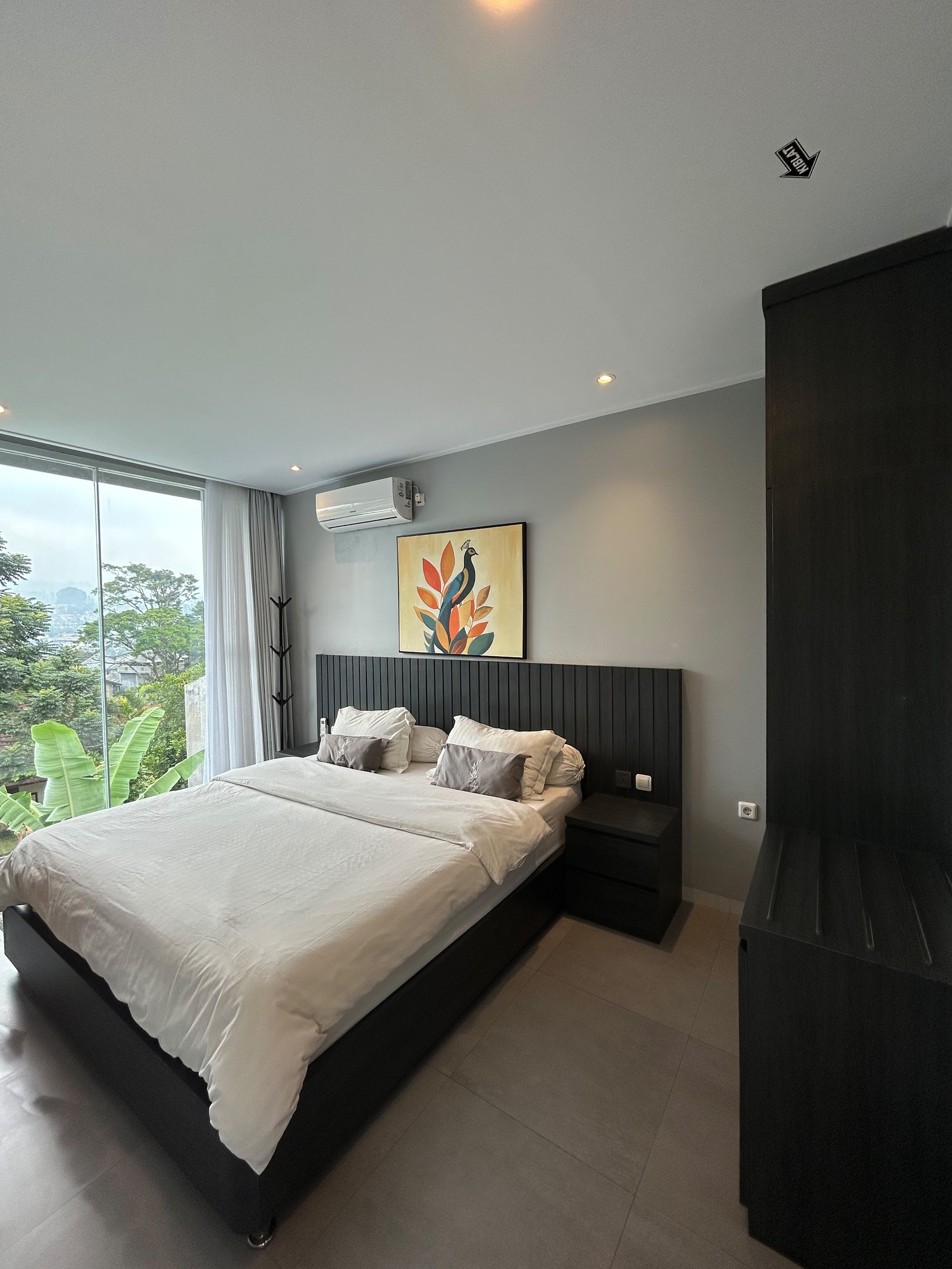 King bed with artwork beside the window at Armada Resort